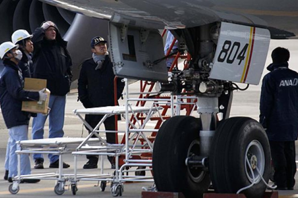 A US Federal Aviation Administration technical advisor (third left) and a member of Japan Transport Safety Board (fourth left) inspect the Dreamliner plane that made an emergency landing on Wednesday. Photo: Reuters