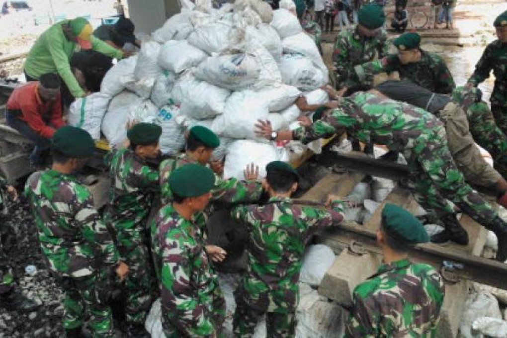 Indonesian military stack sandbags to stop the flow of water from a collapsed river wall in Jakarta on January 19. Photo: AFP