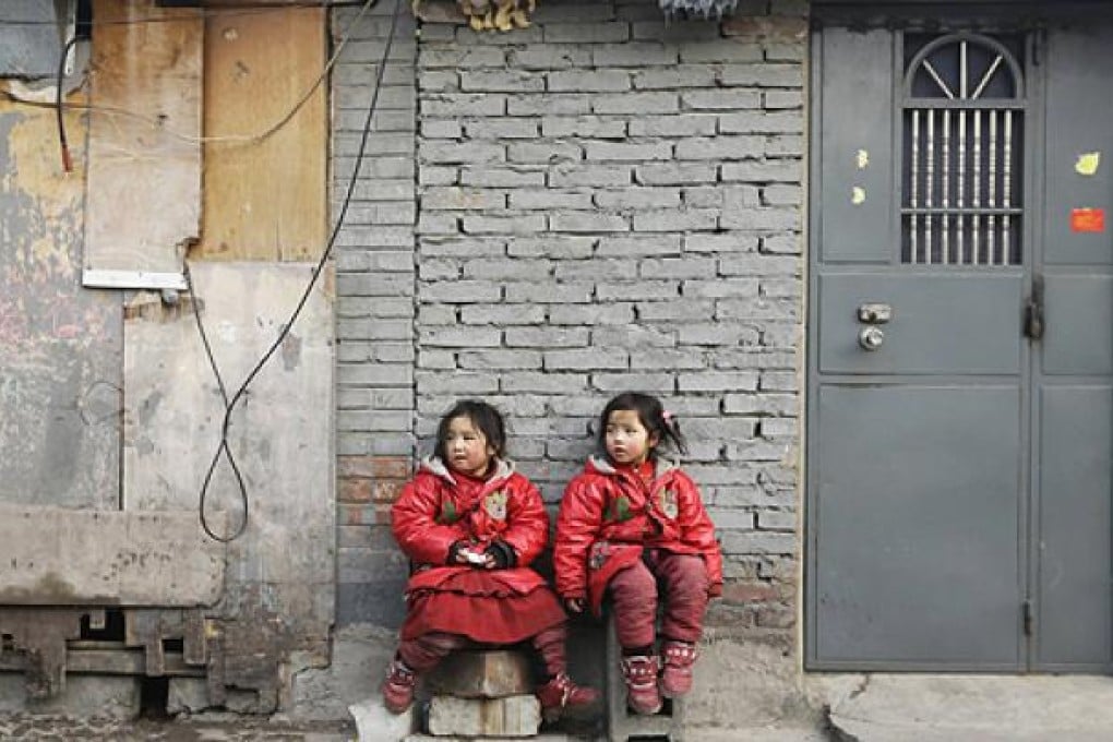 Twin sisters rest against a wall in a poor residential area for migrant workers on the outskirts of Beijing. The capital will release an inequality index for last year. Photo: Reuters
