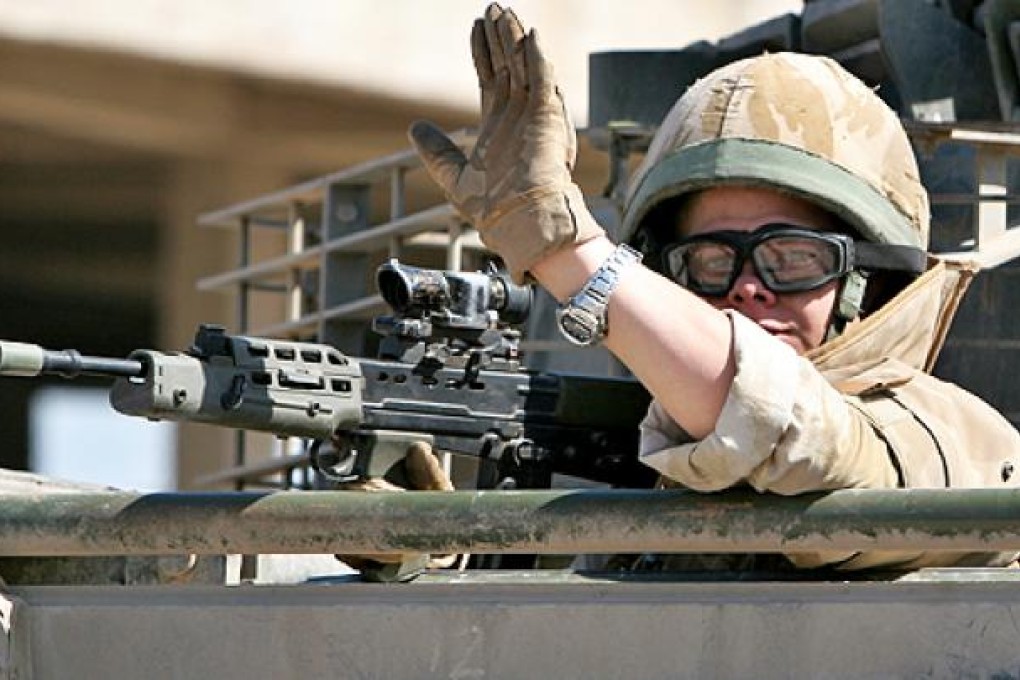 A British army soldier waves from an armoured vehicle while on patrol in Basra, Iraq. Photo: AP