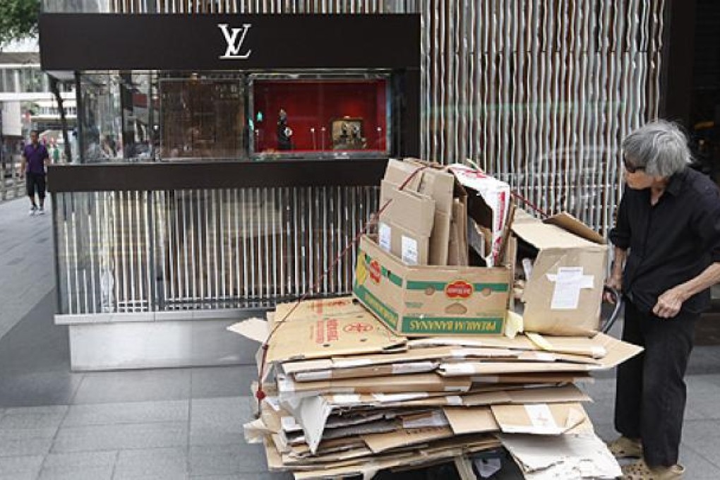 An elderly woman in Central pushes a trolley loaded with cardboard boxes for recycling. Photo: EPA
