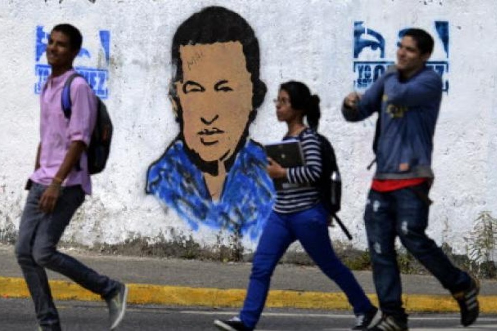 Youngsters walk in front of a banner of Venezuelan President Hugo Chavez in Caracas. Photo: AFP
