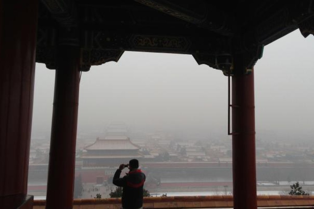 A tourist takes photos of the Forbidden City in smog in Beijing on Jan 23, 2013. Photo by Simon Song
