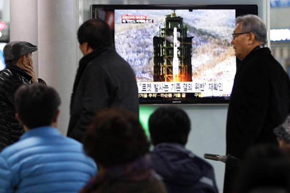 Commuters watch footage of North Korea's December rocket launch at Seoul's main rail station on Wednesday. Photo: AP