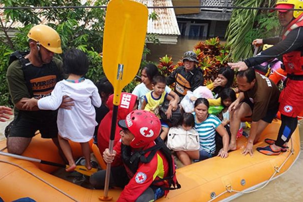 Red Cross staff and volunteers equipped with rubber boats bring residents to safety in Davao, Philippines. Photo: EPA