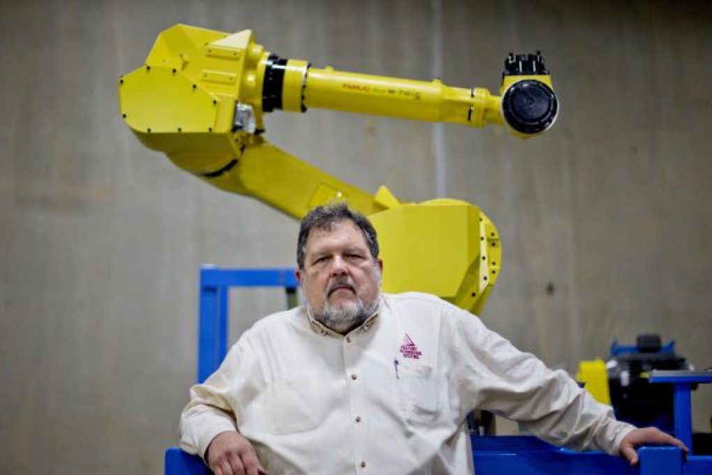 Rosser Pryor, co-owner and president of Factory AutomationSystems, sits beside a new high-performance industrial robot at the company's Atlanta facility. Pryor, who cut 40 of 100 workers since the recession, says while the company could afford to hire 10 people, but wants to invest in automation. The company is a striking example of the way automation and technology are eliminating jobs. Photo: AP
