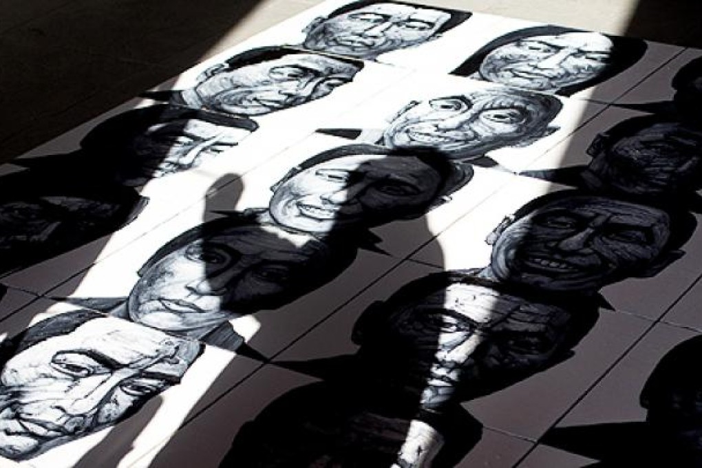 A Beijing artist lays out his portraits of Tibetans who have self-immolated. Photo: AP