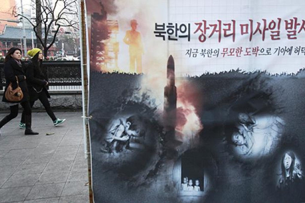 A banner showing starving North Korean children and a rocket is displayed on a street in Seoul on Thursday. China will decrease aid to Pyongyang if it goes ahead with a planned nuclear test. Photo: AP
