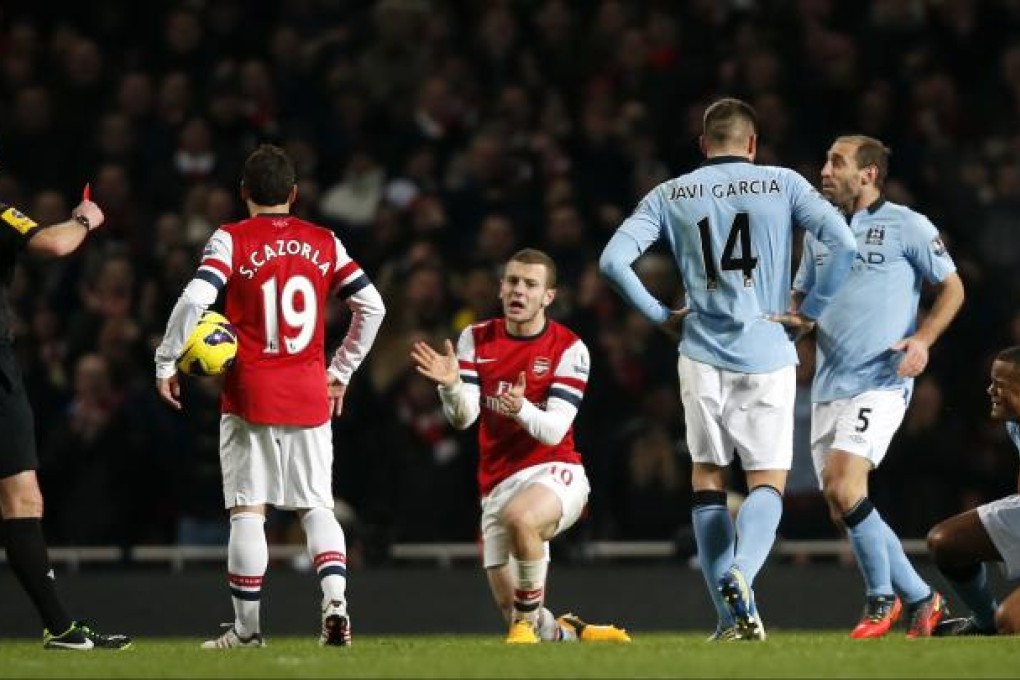 Referee Mike Dean (1st left) shows Manchester City's Vincent Kompany (1st right) a red card for his tackle of Arsenal's Jack Wilshere (3rd left). Photo: Xinhua