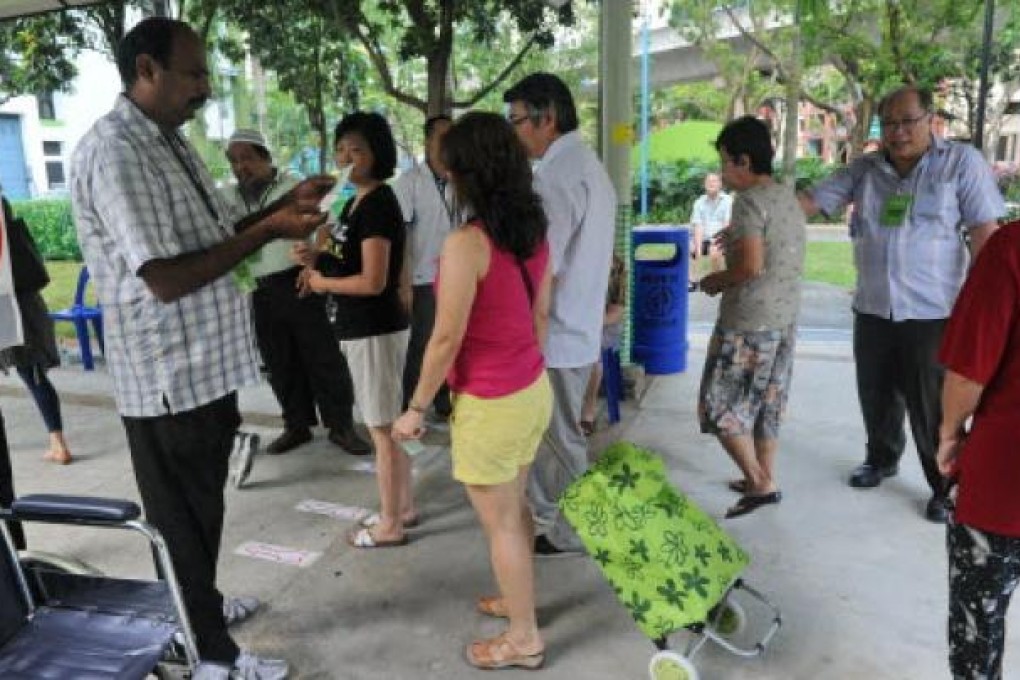 Presiding officers check the particulars of voters at the entrance to a polling station in Singapore on Saturday. Photo: AFP