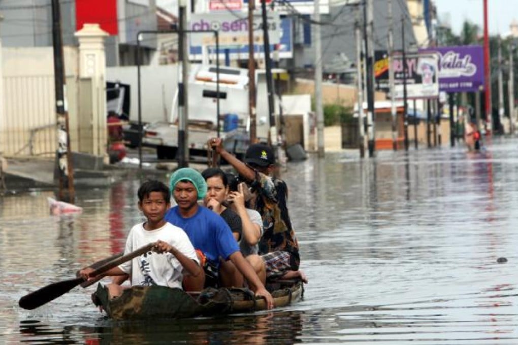 Local residents ride on a bamboo raft in a flooded street in northern Jakarta. Photo: AP