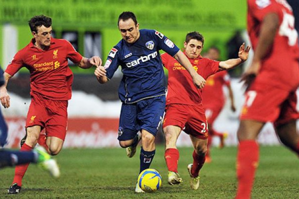 Oldham's Lee Croft (centre) takes on Liverpool players. Photo: AFP