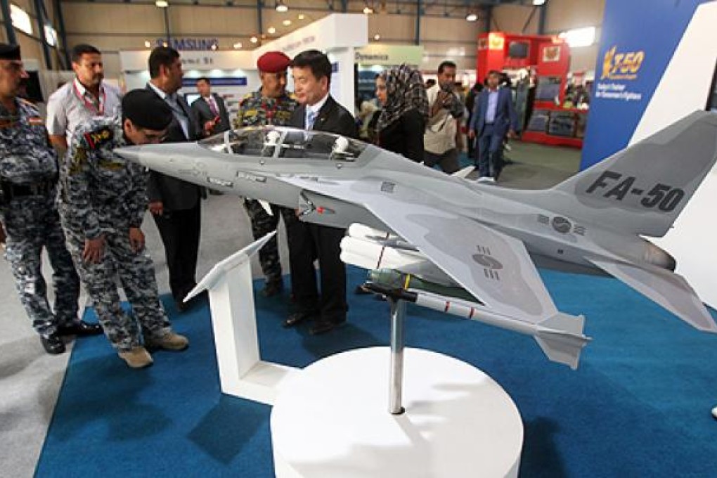 Officials and military staff look at a FA-50 fighter jet model at Baghdad's International Fair for Defence and Security. Photo: AFP