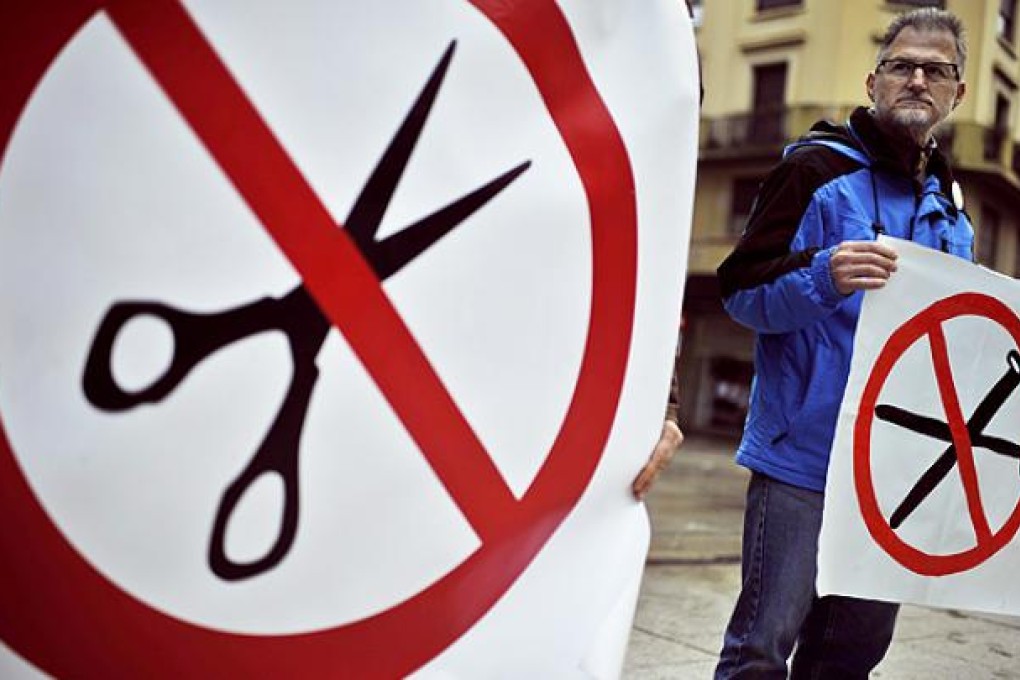 A state worker holds up a banner protesting against austerity measures by Spanish regional governments in Pamplona, northern Spain. Photo: AP