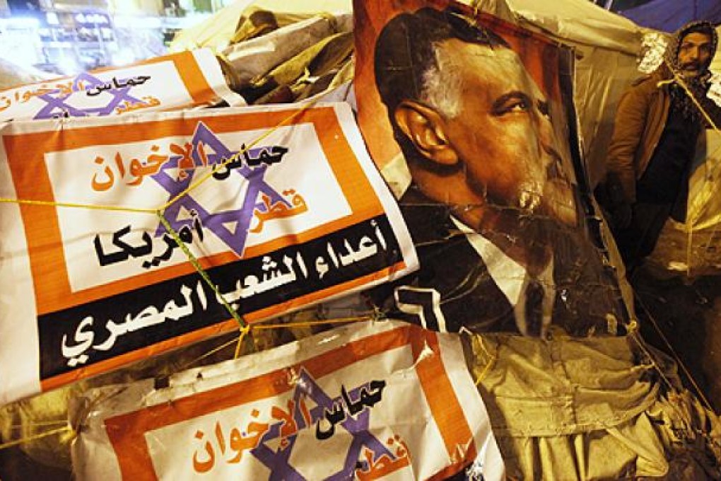 A protester opposing Egyptian President Mursi walks outside tents near a picture Egypt's former President Nasser during a sit-in at Tahrir Square. Photo: Reuters