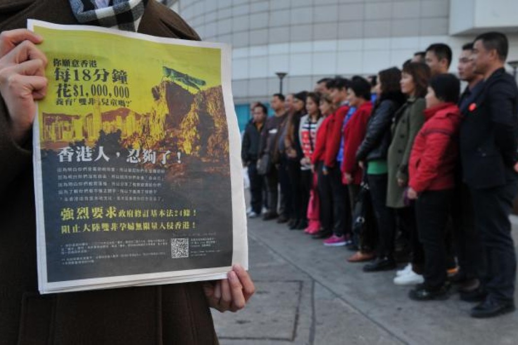 A girl holds a Hong Kong newspaper with an anti-mainland China advertisement with a picture of a locust looking over the Hong Kong cityscape as Chinese mainlanders pose for a picture in the background. Photo: AFP