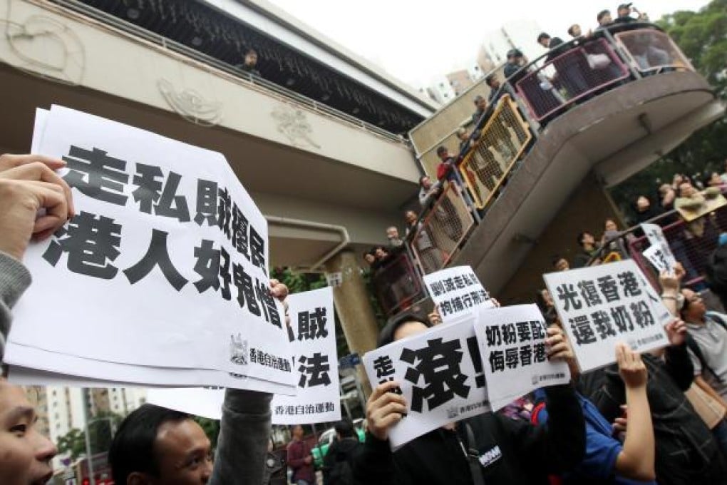 Concern groups continue to rail against parallel traders from the mainland outside Sheung Shui station yesterday. Photo: David Wong