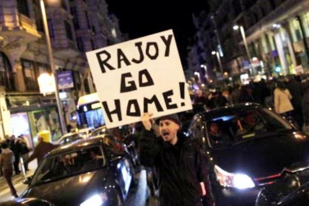 Protestors shout slogans and wave banners placards reading "Rajoy go home" during a demonstration against corruption in Madrid, on Saturday. Photo: AP