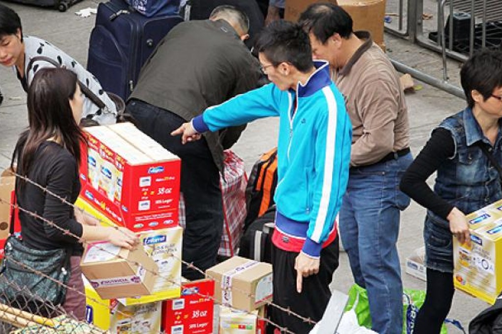 People repackage milk powders into smaller luggages outside Sheung Shui train station on Monday after the government announced a series of measures to crack down on parallel trading of milk powders last week. Photo: Nora Tam