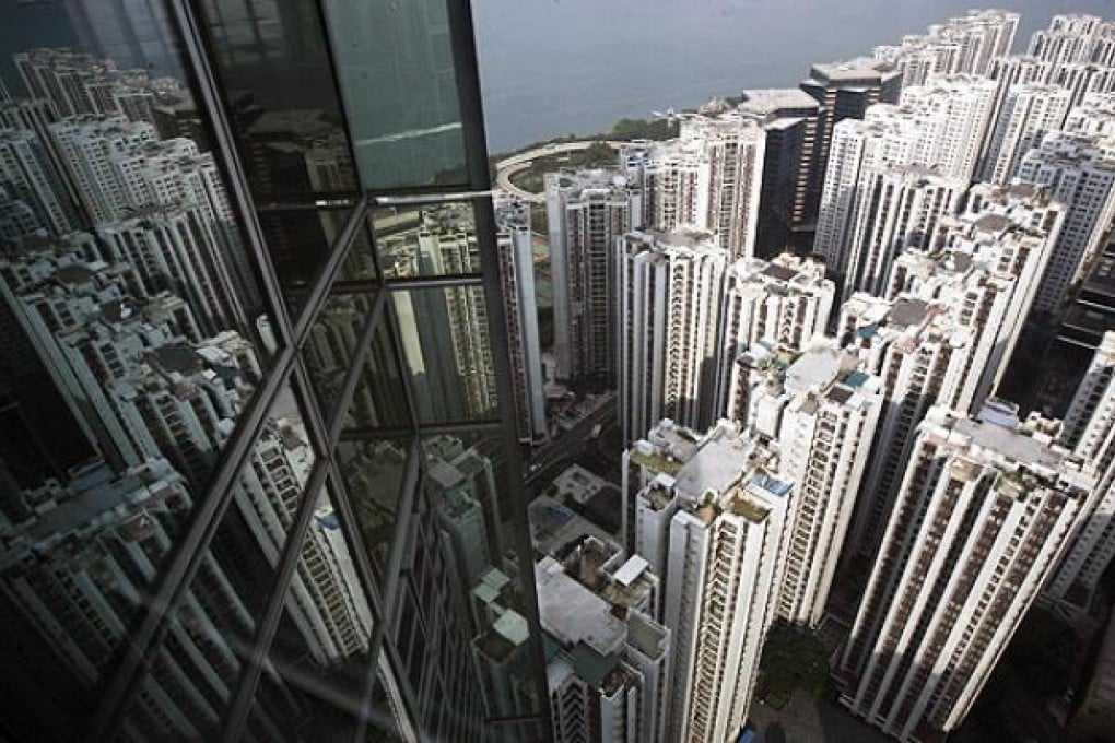 Residential blocks are reflected on the glass panes of a business tower in North Point. Photo: Reuters