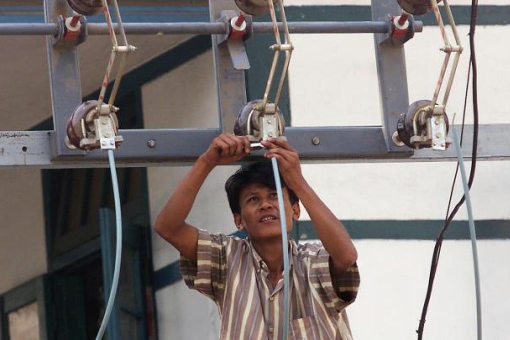 A technician fixing power lines above a street in Yangon. Three out of four people in Myanmar are without reliable access to electricity. Photo: AFP