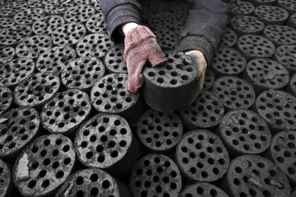 A worker moves coal briquettes onto a pedicab at a coal distribution business in Huaibei, Anhui province on January 30, 2013. Photo: AFP