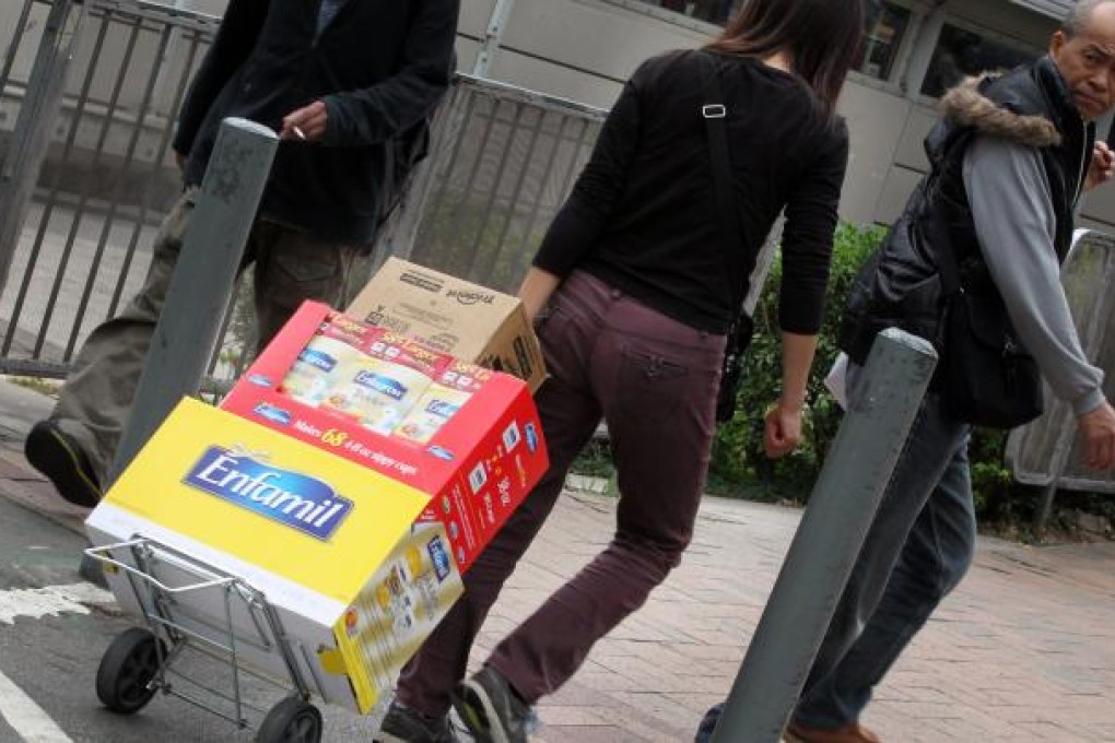 A woman carries milk powders outside Sheung Shui train station. The government announced a series of measures to crack down on parallel trading of milk powders last week. Photo: Nora Tam