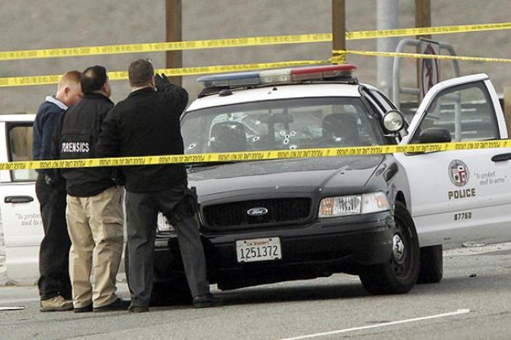 Investigators inspect an LAPD vehicle riddled with bullet holes in Corona, California. Photo: Reuters
