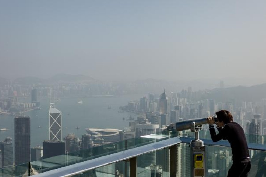 A tourist uses binoculars to view the city's skyline over a thin haze of pollution on a clear day in Hong Kong on February 1, 2013. Photo: AFP