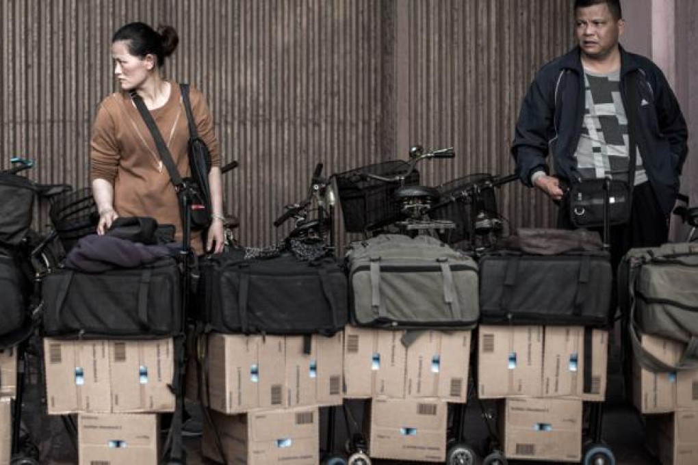 People transporting boxes filled with baby formula queue up to get their package weighted at the Sheung Shui train station prior to their journey back to mainland China. Photo: AFP