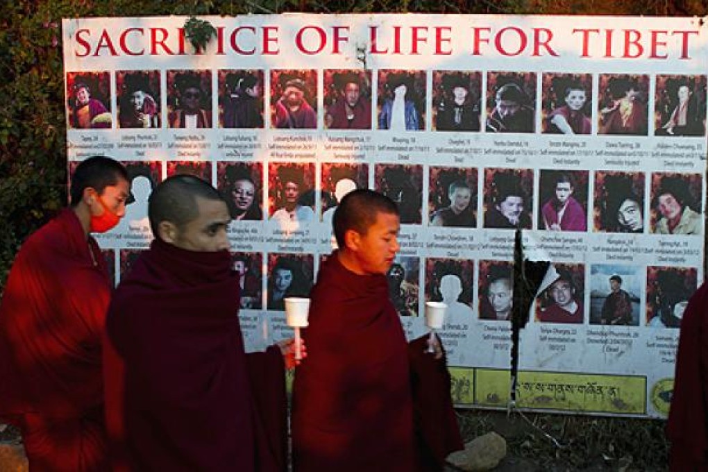 Exiled Tibetan Buddhist monks walk past photos of Tibetan protesters as they participate in a candlelit vigil to show solidarity with Tibetans in Tibet. Photo: AP