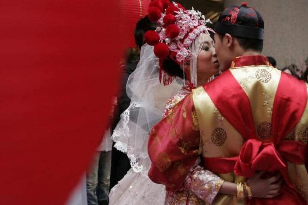 Rain Siu Wingshan (L) and Zero Yau Man-hong (R) kiss after their traditional chinese wedding ceremony outside a shopping centre in Hong Kong's Causeway Bay district on February 14, 2010. Photo: AFP