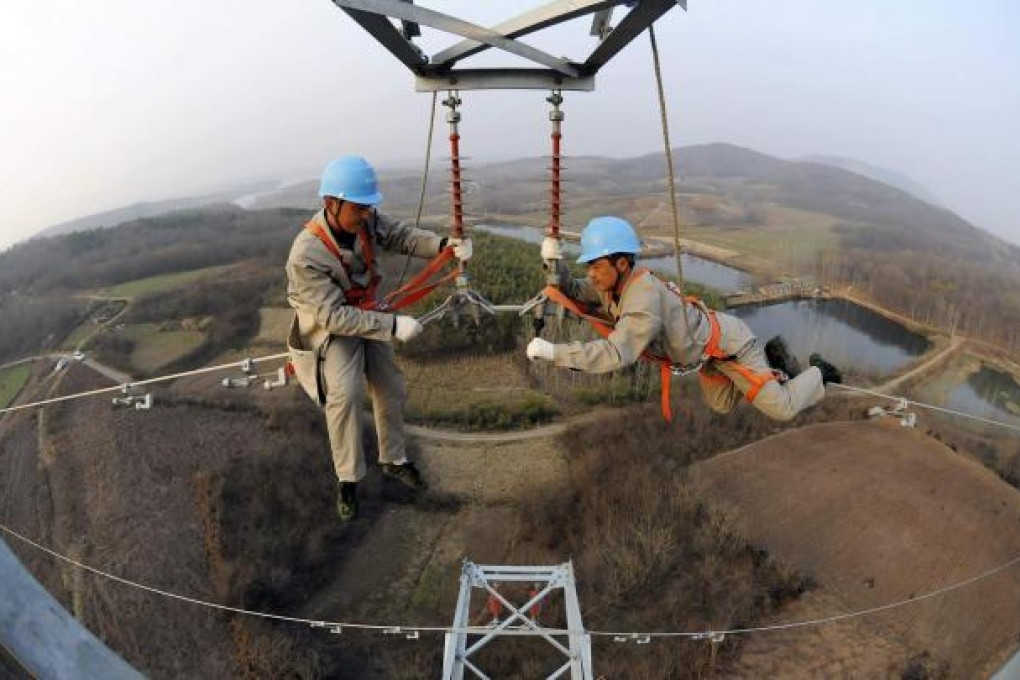 Workers check on an electricity pylon supplying power to rural areas and farmlands of Chuzhou, in Anhui province. Photo: Reuters