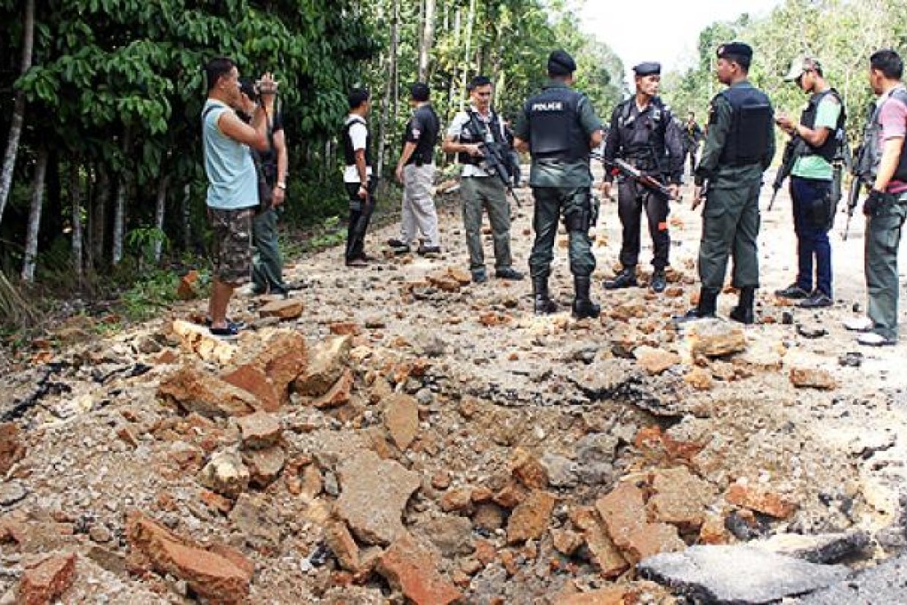 Thai policemen inspect the site of a roadside bomb attack by suspected separatist militants on Sunday. Photo: AFP