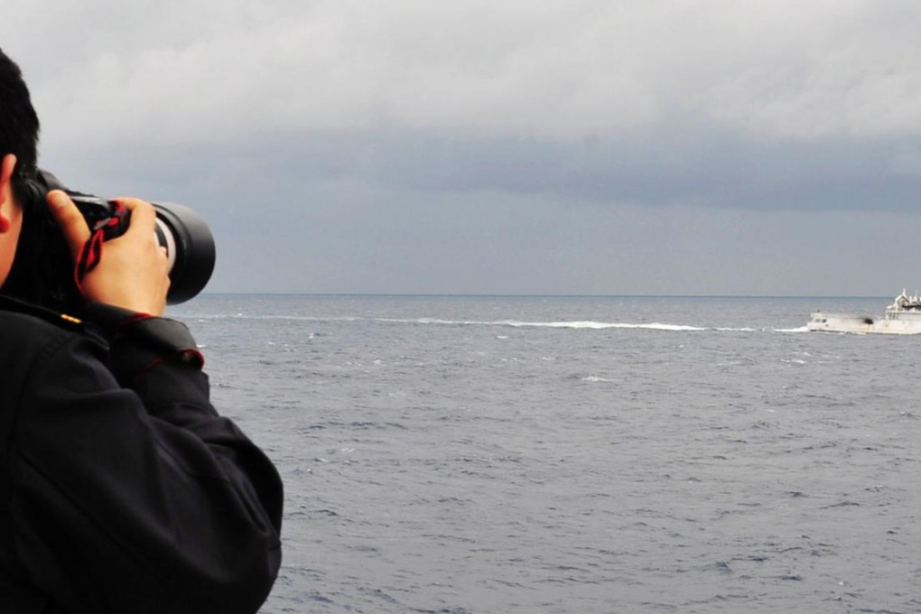 A China Marine Surveillance officer photographs a Japan Coast Guard vessel near the disputed Diayou Islands yesterday. Photo: Xinhua