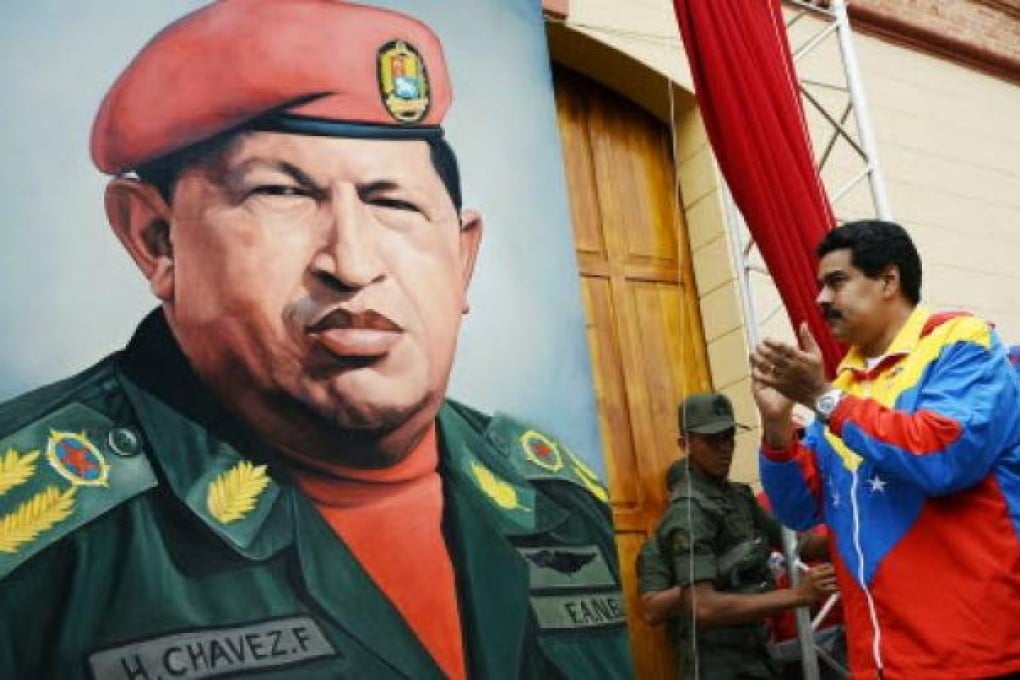 Venezuelan Vice President Nicolas Maduro (R) looks at a portrait of Venezuelan President Hugo Chavez. Photo: AFP