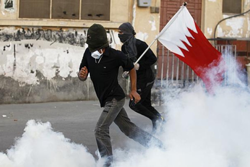 Anti-government protesters, one of them holding a Bahraini flag, run to take cover from tear gas in the village of Sanabis. Photo: Reuters