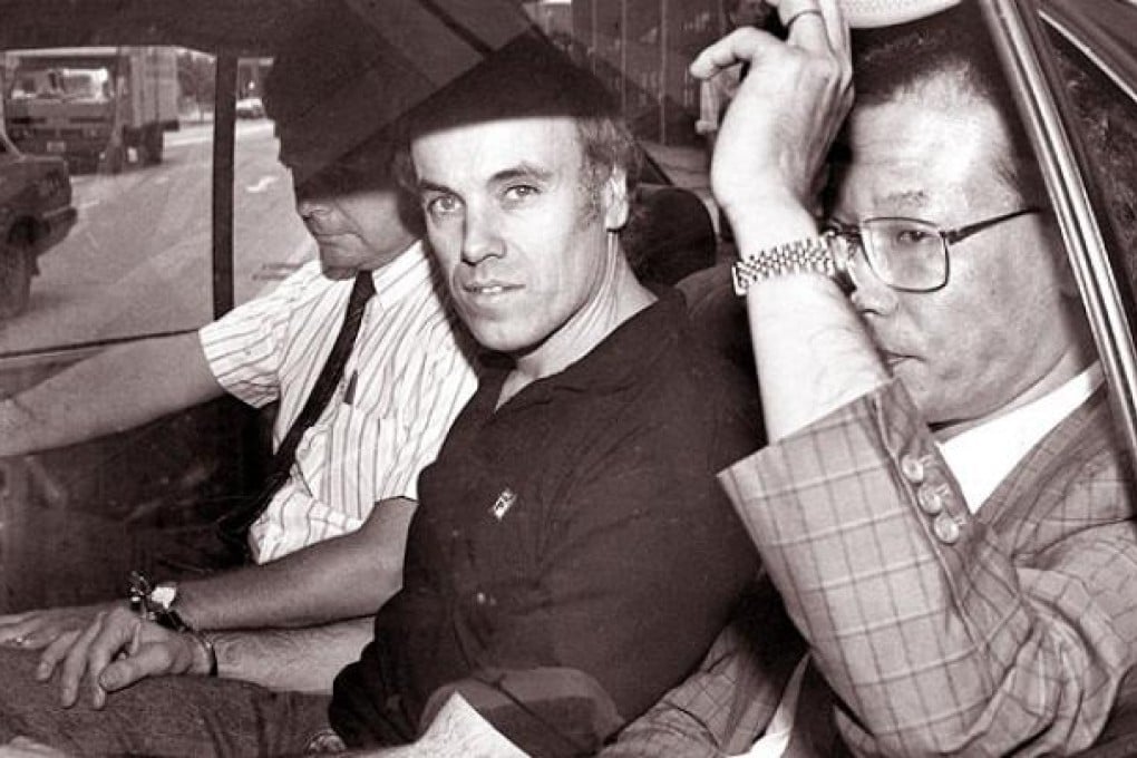 Warwick Reid flanked by police after a court hearing in 1990. Photo: Robert Ng