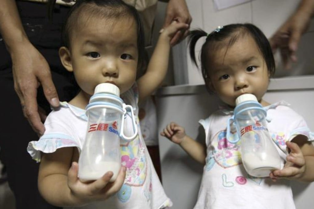 Two girls drink milk from Sanlu brand bottles while waiting to be checked for kidney stones at a children's hospital in Shenzhen. Photo: AP