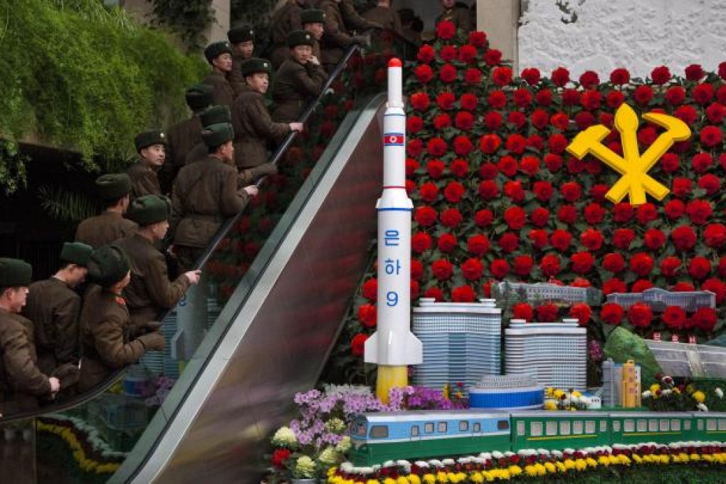 North Korean soldiers ride an escalator past a model of their country's Unha Rocket as they enter an exhibition in Pyongyang. Photo: AP