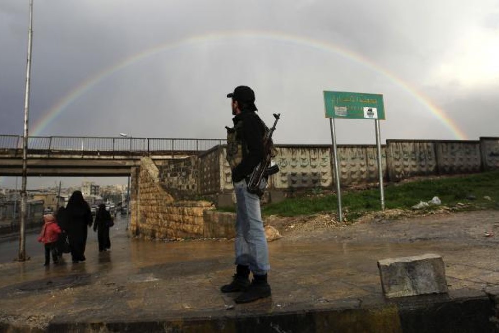 A member of the Free Syrian Army stands with his weapon as he looks at a rainbow in Aleppo on Saturday. Photo: Reuters