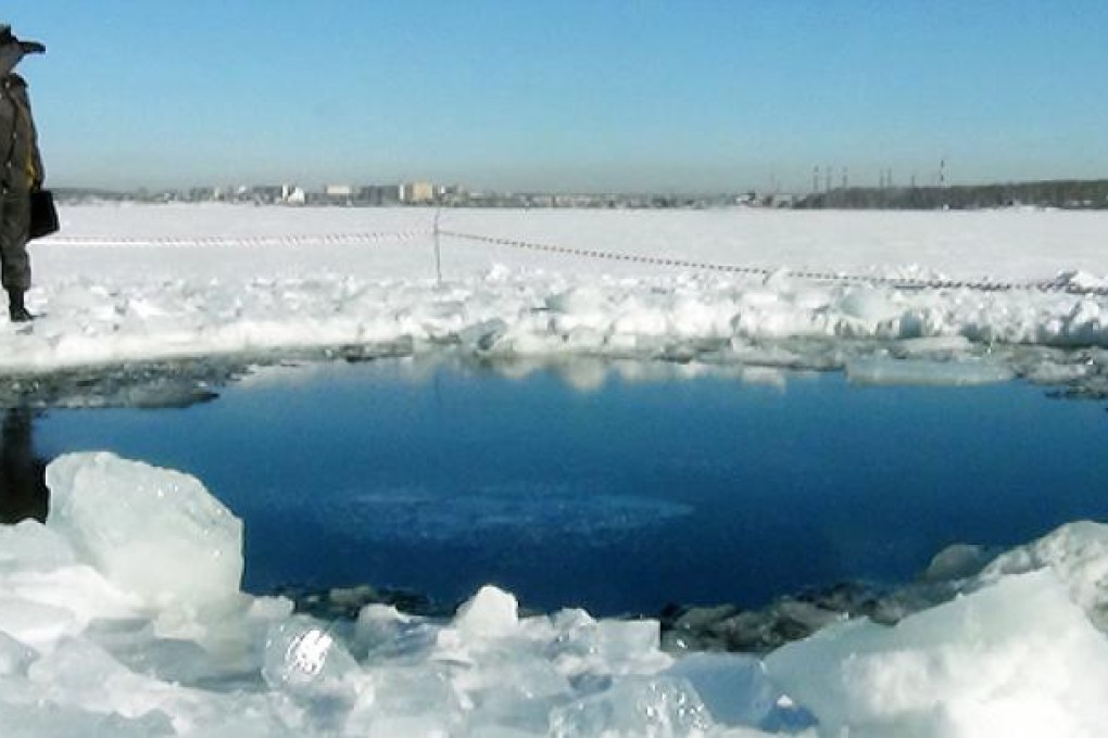 A police officer stands near a six-metre hole in the ice of a frozen lake, reportedly the site of a meteor fall, outside the town of Chebakul. Photo: AFP