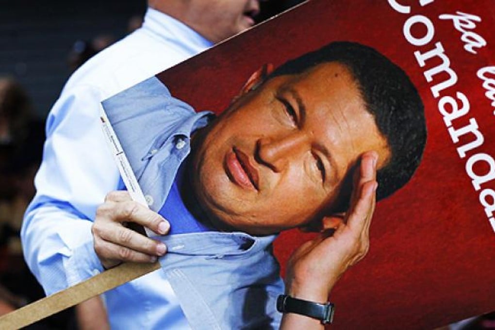A supporter of Venezuelan President Chavez holds a picture of him as he takes part in a gathering at Plaza Bolivar in Caracas on Monday. Photo: Reuters