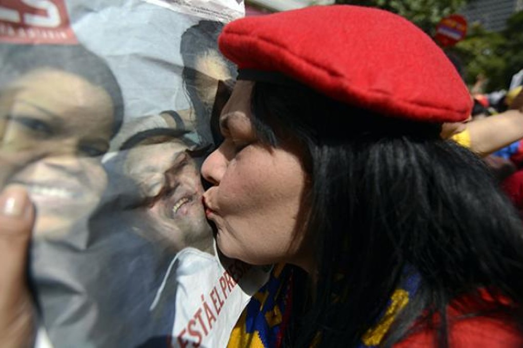 A woman kisses a picture of Venezuelan President Hugo Chavez as supporters gather at Simon Bolivar Square in Caracas. Photo: AFP