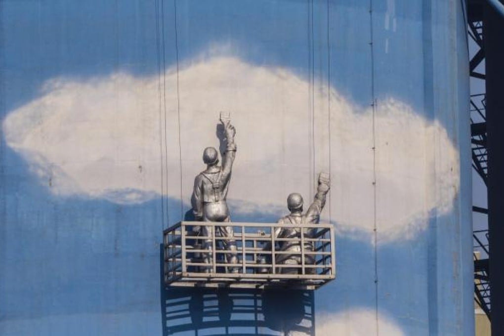Statues of workers appearing to paint the sky blue decorate storage tanks at a clean-energy heating plant in Beijing. Photo: EPA