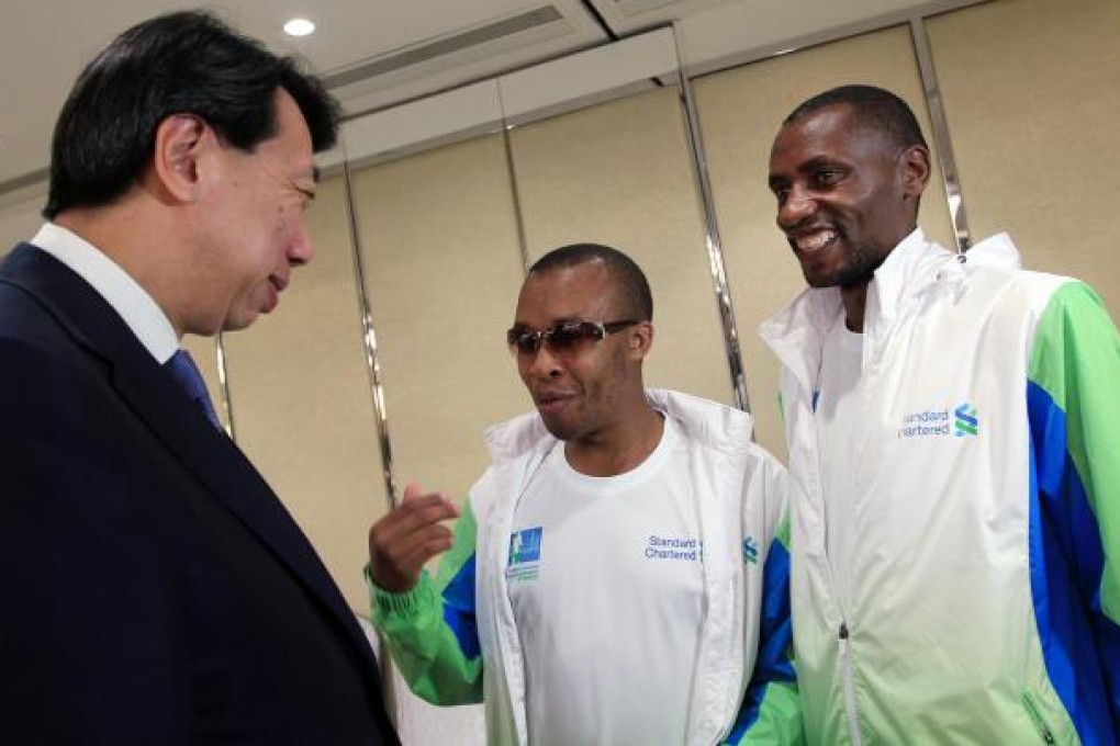 Standard Chartered chief executive Benjamin Hung Pi-cheng chats with blind Paralympics marathon medallist Henry Wanyoike (centre) and his guide Joseph Kibunja. Photo: Jonathan Wong