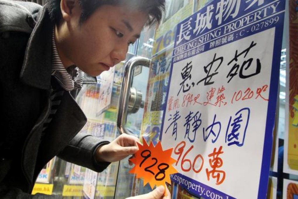 An estate agent revises the price of a Tai Koo property listing downward after new measures to curb home prices were announced yesterday. Photo: Sam Tsang