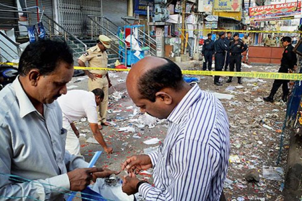 Officials of India's National Investigation Agency collect evidence in the debris at one of the two bomb blast sites, in Hyderabad, on Friday. Photo: AP