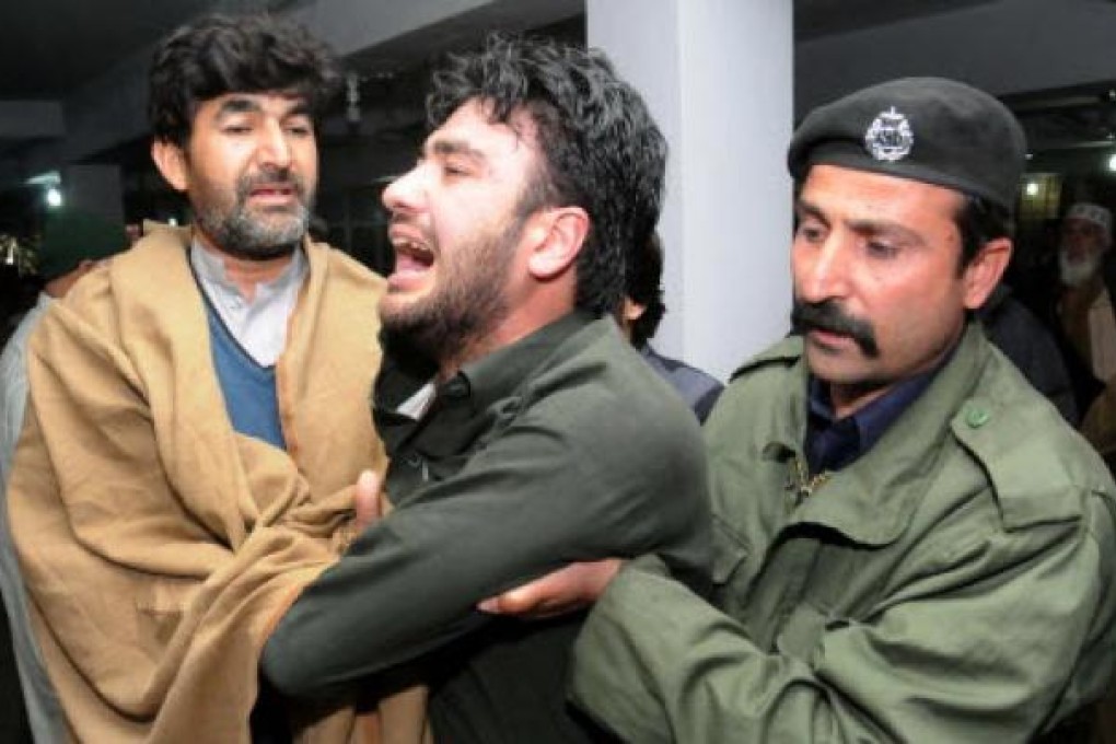 People comfort a man whose relative was killed when a bus fell into a Canal, at a local hospital in Peshawar. Photo: EPA