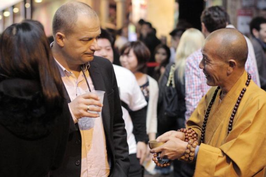 A bogus Buddhist monk, an all-too-familiar sight in Hong Kong these days, holds out his begging bowl to a drinker in Lan Kwai Fong. An influx of 'monks' from the mainland on tourist visas has led to calls for tighter immigration rules. Photo: Paul Yeung